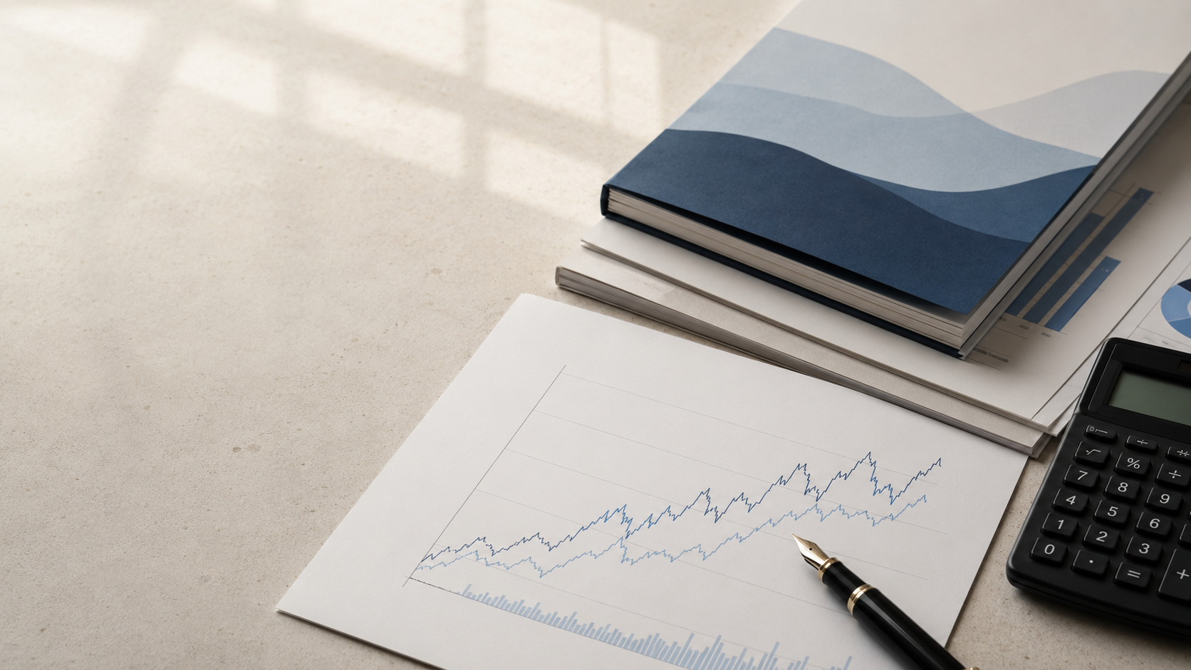 Research reports, a valuation chart, fountain pen and calculator on an analyst's desk